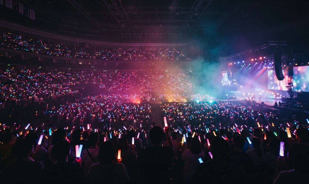Fans holding glowing light sticks at a K-pop concert
